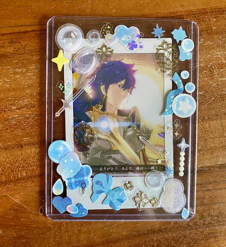 a photocard of chrom from fire emblem awakening decorated in
                                                             blue and gold stickers, including some slightly 3D
                                                             gold ones.